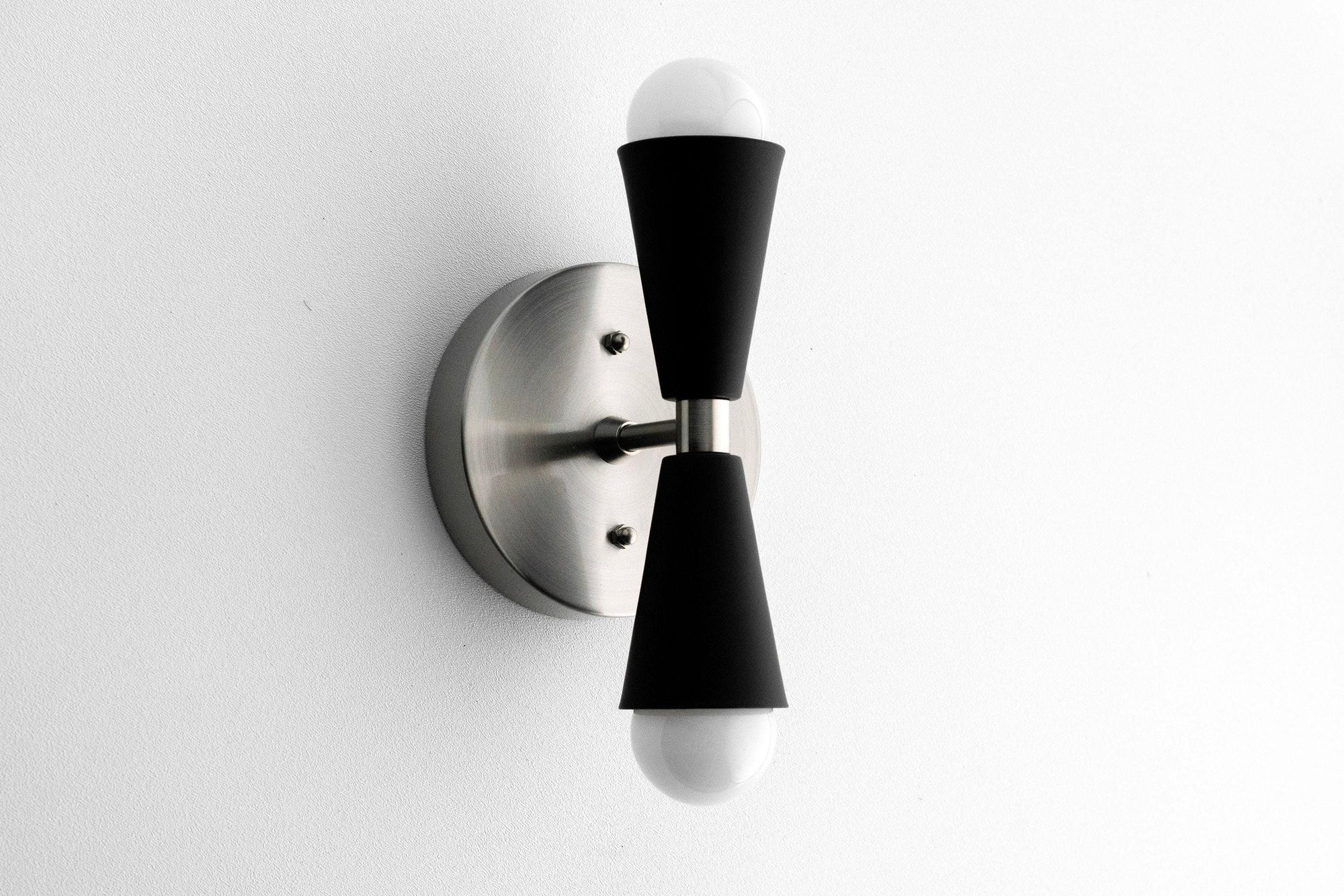 Mid-century modern brushed nickel wall sconce with black tapered holders and bare bulbs up and down. - SCONCE MODEL NO. 4717