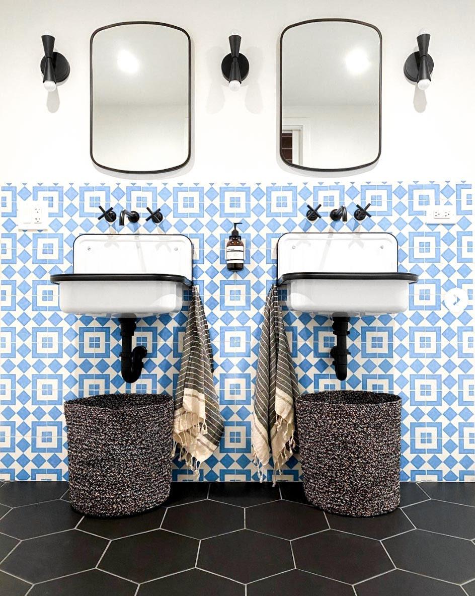Mid-century modern black up/down wall sconces flanking rectangular mirrors over double sinks with patterned blue and white. - SCONCE MODEL NO. 4717