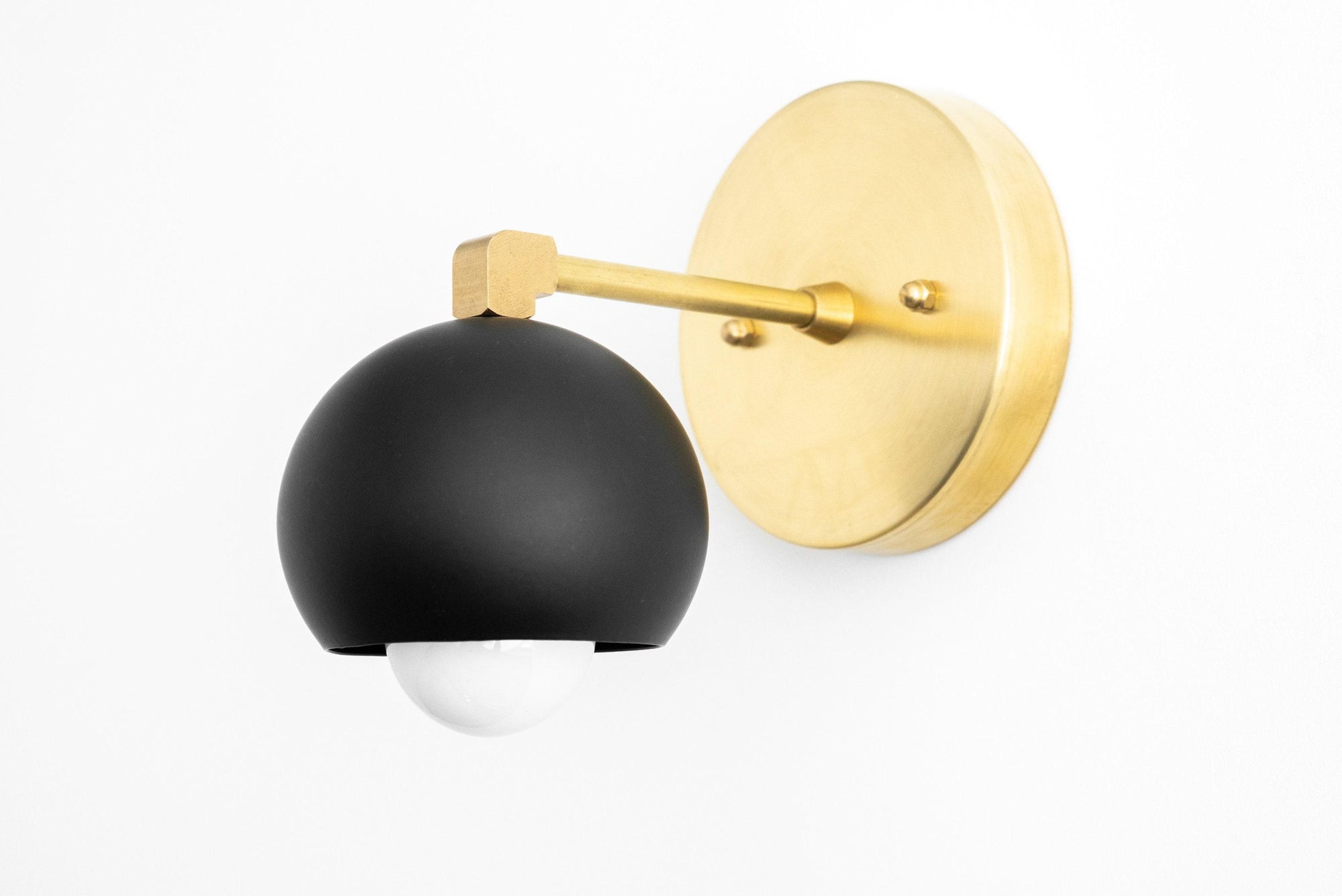 Wall sconce with matte black dome shade and raw brass round backplate and arm. - SCONCE MODEL NO. 0053
