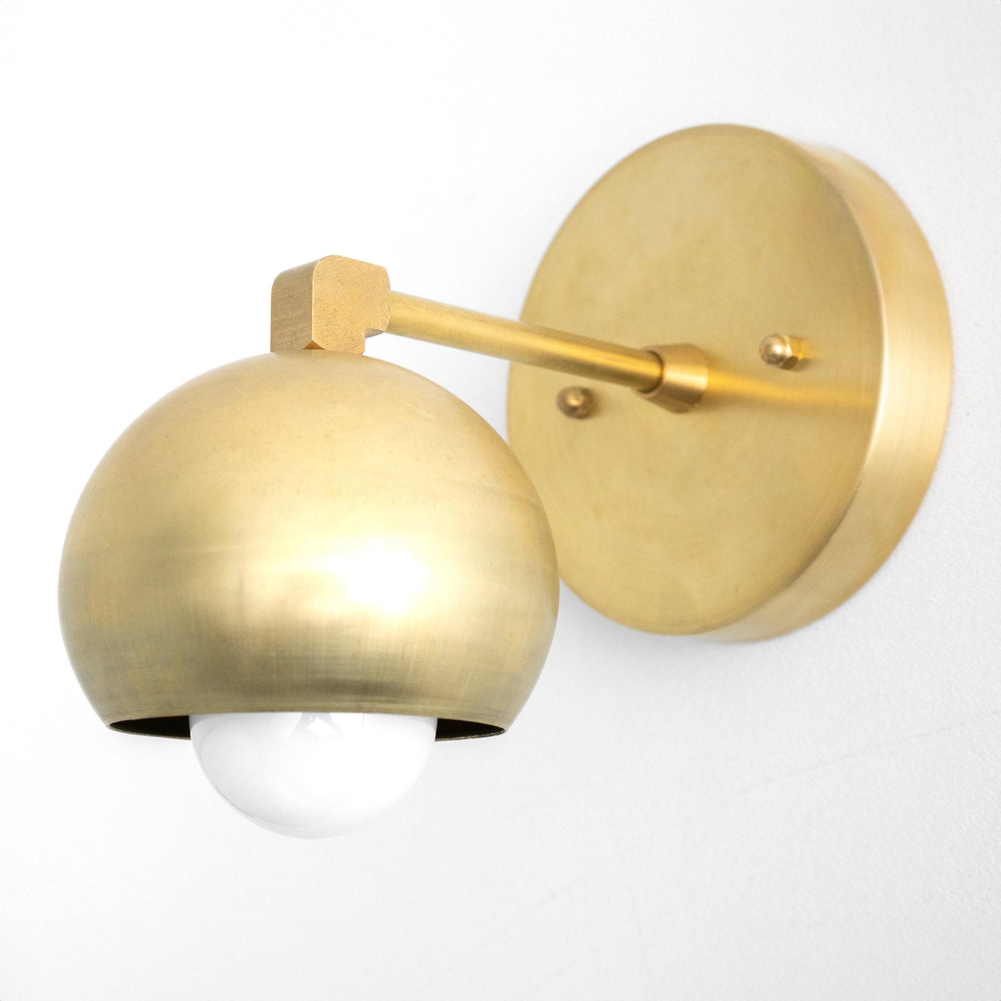 Mid-century modern raw brass sconce with a dome-shaped shade and exposed bulb design. - SCONCE MODEL NO. 0053