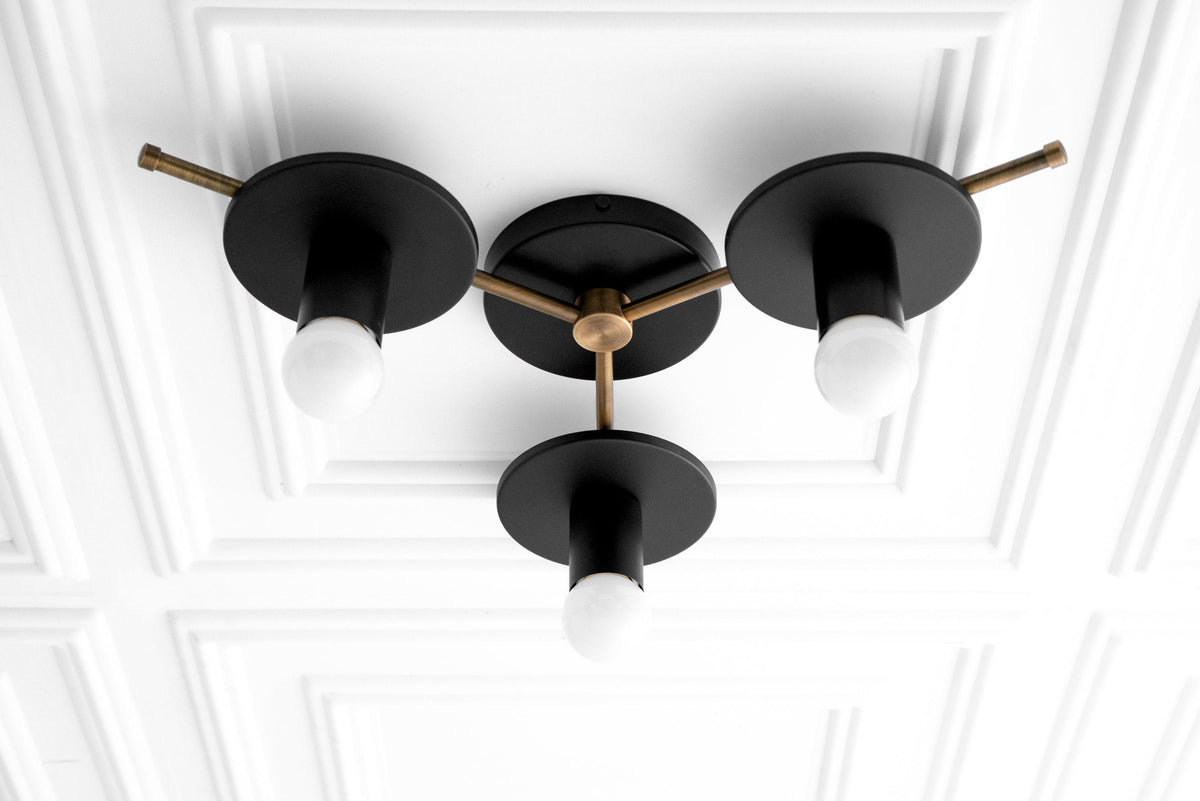 Mid-century modern flush mount chandelier with three black matte arms and exposed white bulbs on an antique brass fixture. - CHANDELIER MODEL NO. 9526