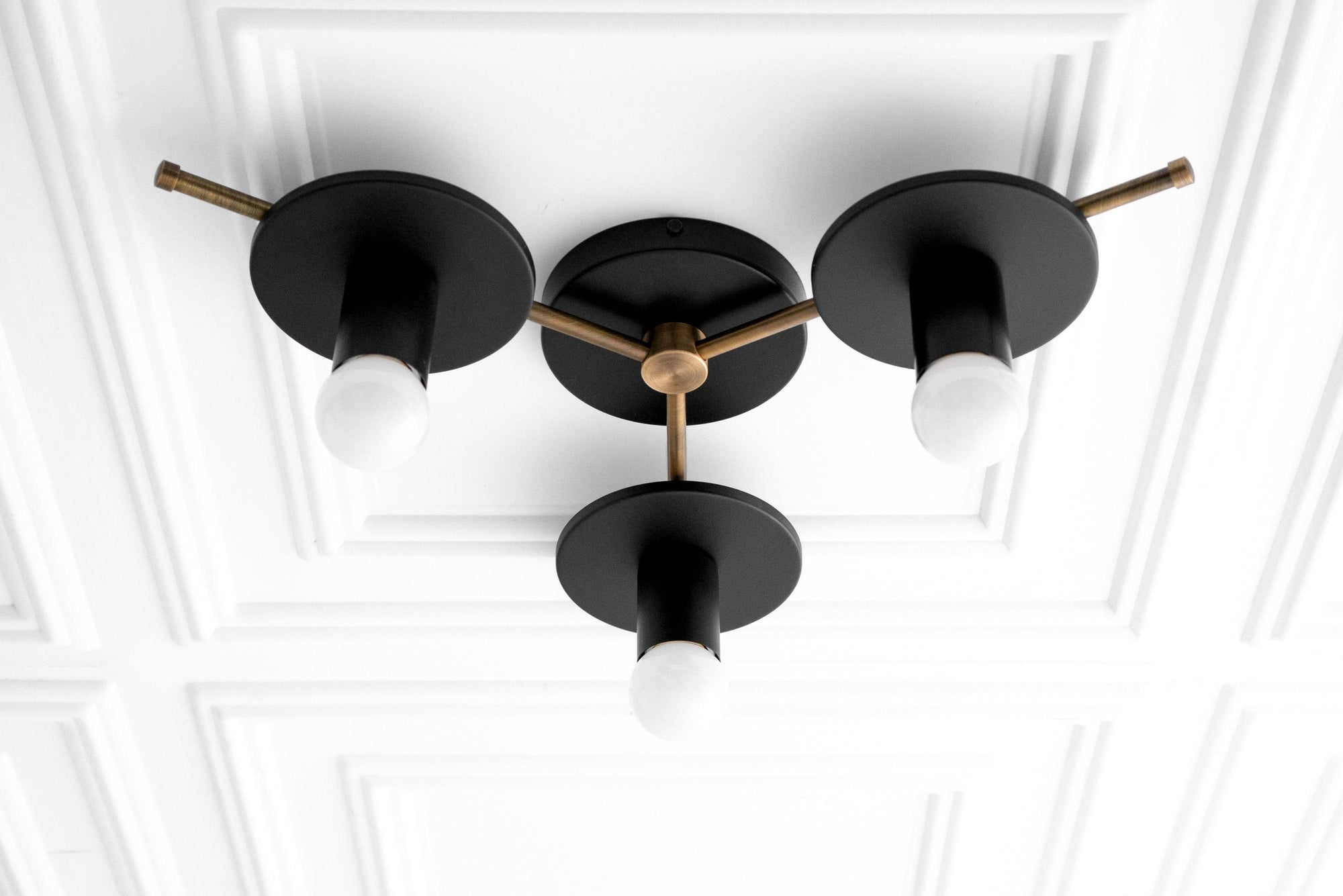 Mid-century modern flush mount chandelier with three black matte arms and exposed white bulbs on an antique brass fixture. - CHANDELIER MODEL NO. 9526