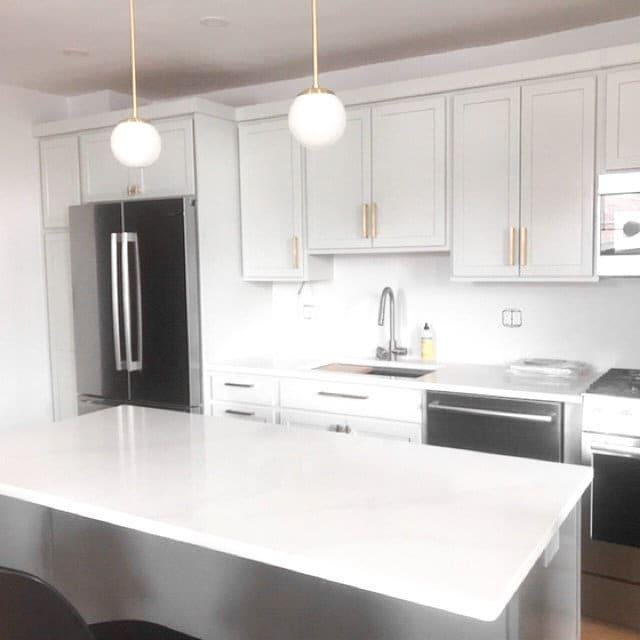 Mid-century modern pendant light with white globe and brass fixture above white kitchen island. - PENDANT MODEL NO. 7056