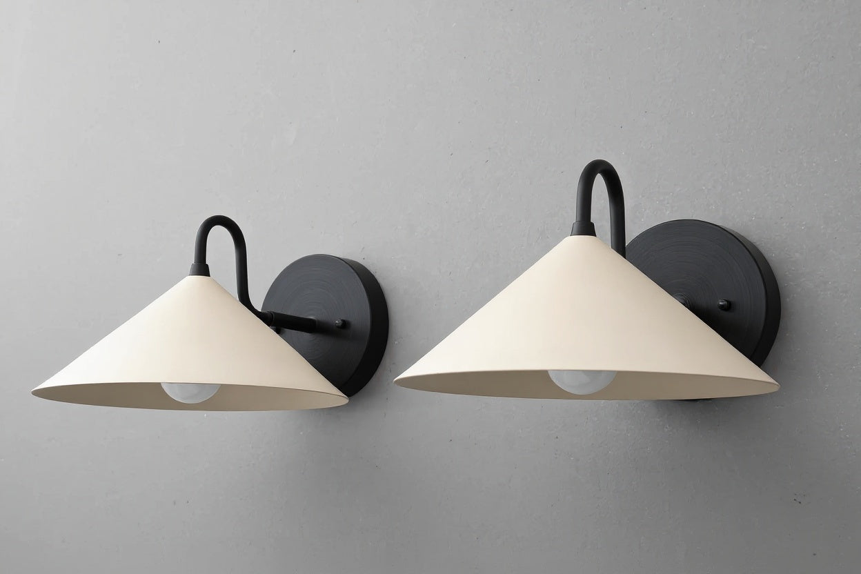 Pair of wall sconces with conical cream shades and matte black metal mounts against gray wall. - SCONCE MODEL NO. 6528