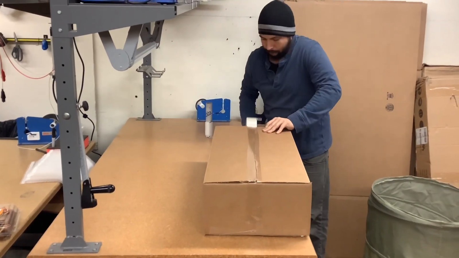 A Peared maker taping shut the shipping box of a finished lamp at the packing bench