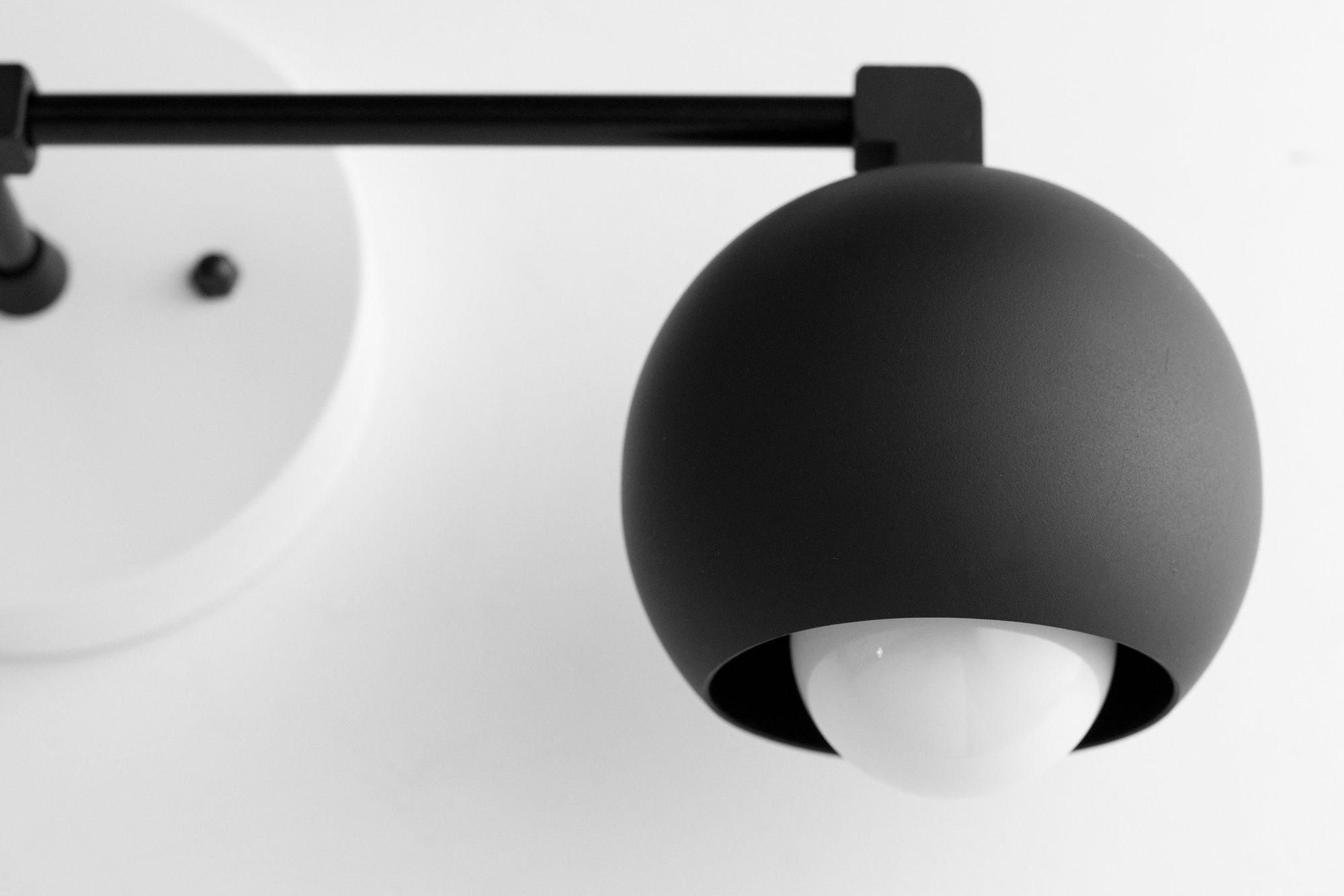Matte black mid-century modern vanity light with spherical shade and exposed bulb. - VANITY LIGHT MODEL NO. 5469