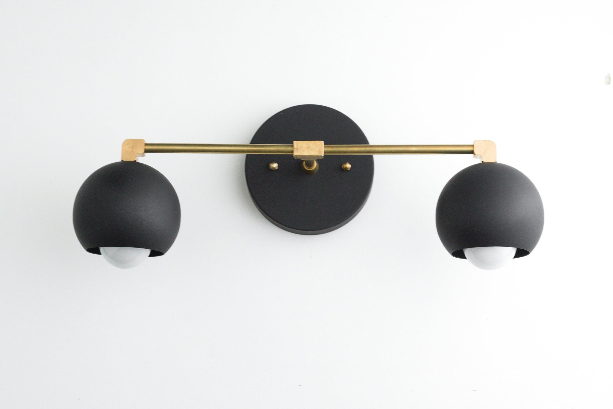 Mid-century modern black and raw brass 2-bulb vanity light with round backplate and globe-shaped shades. - VANITY LIGHT MODEL NO. 5469