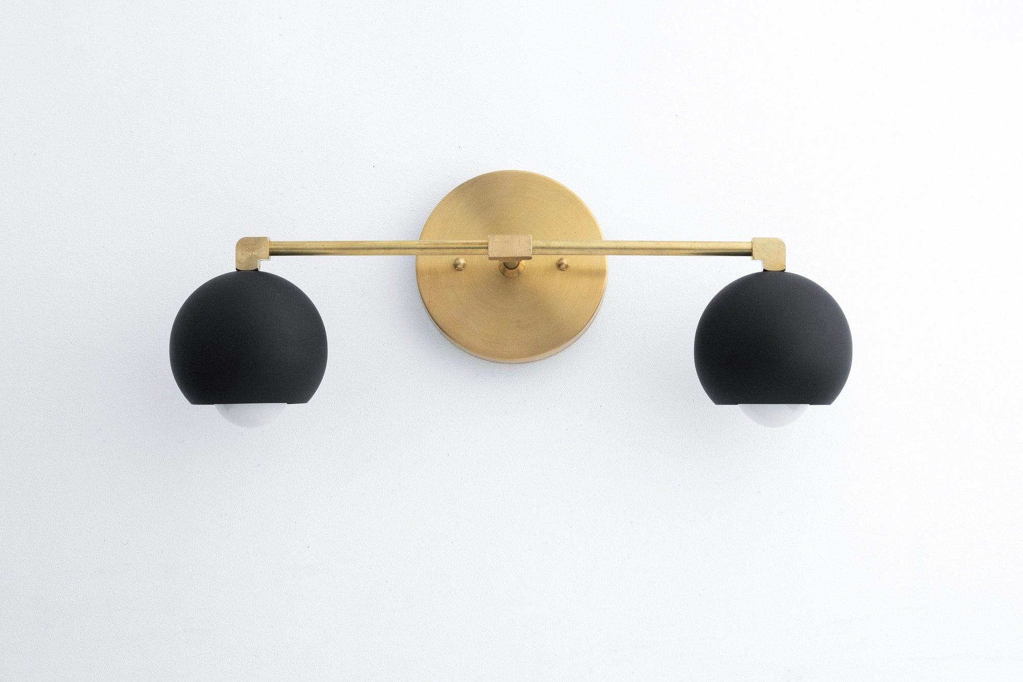 Mid-century modern vanity light with raw brass base and two black spherical shades. - VANITY LIGHT MODEL NO. 5469