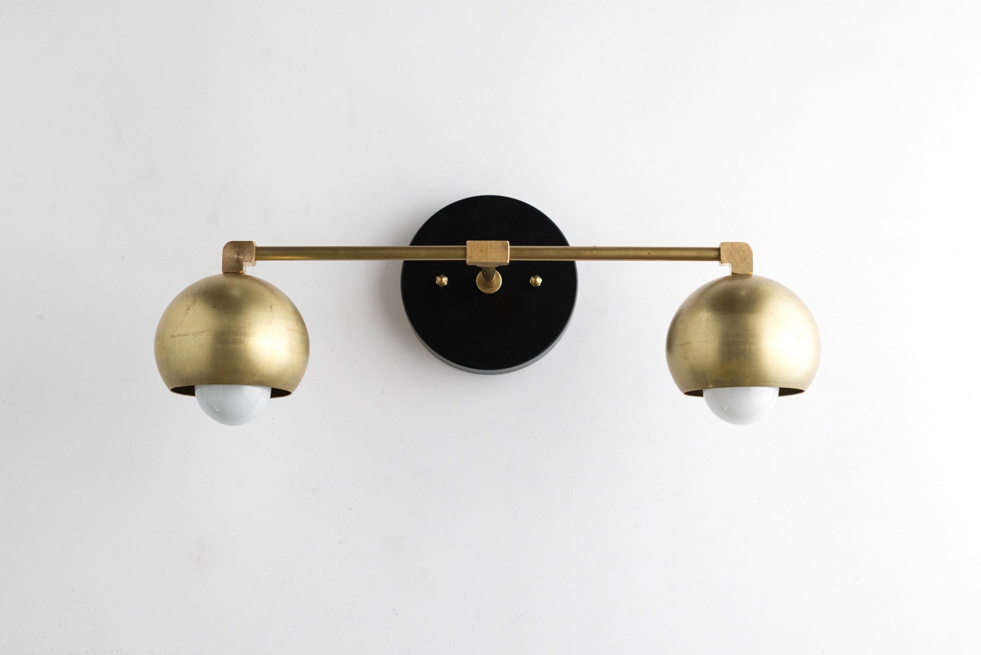 Mid-century modern 2-bulb vanity light with raw brass dome shades and black circular wall mount. - VANITY LIGHT MODEL NO. 5469