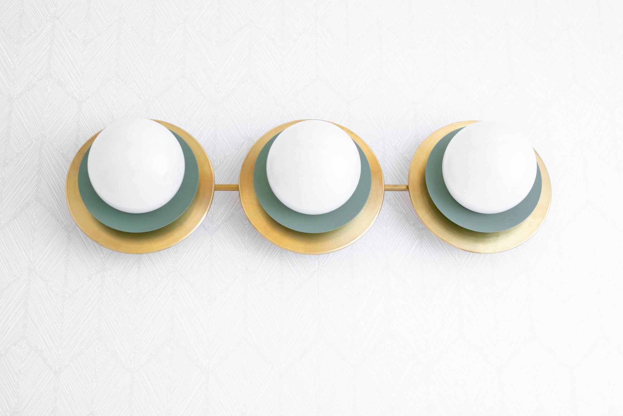 Raw brass vanity light with three white globe bulbs on green backplates, mid-century modern design. - VANITY LIGHT MODEL NO. 7680